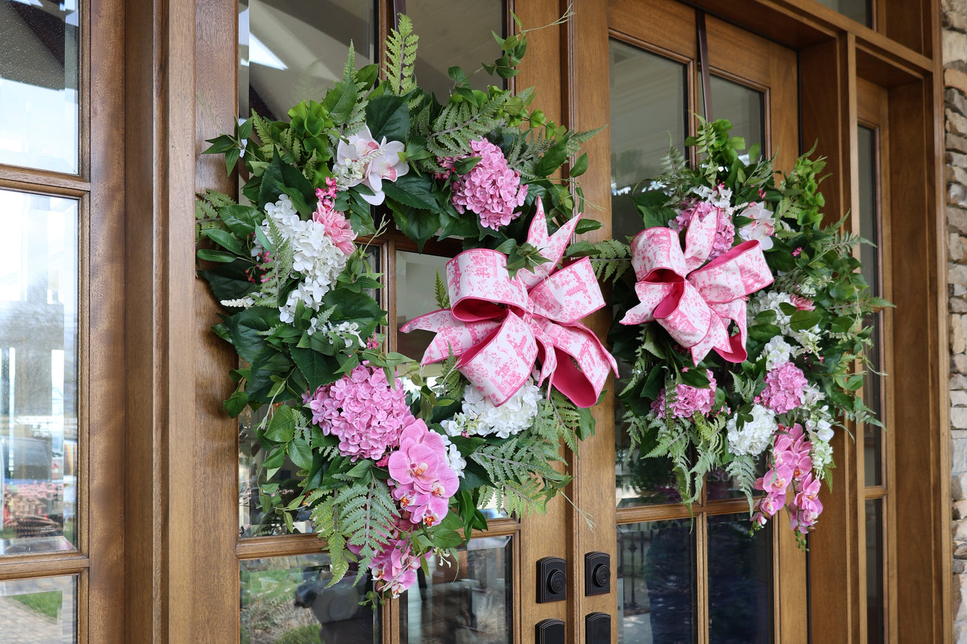 Floral wreath with pink bow on a wooden door