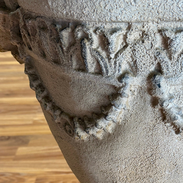 Decorative stone urn on a wooden floor