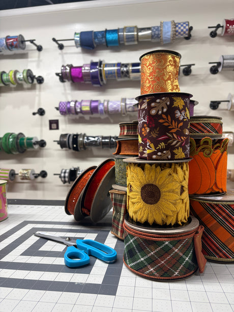 stack of wired  fall ribbons on a craft table with ribbon store in the background
