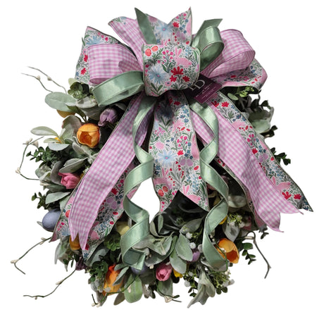 Decorative wreath with pink and green ribbons on a plain background