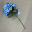 Artificial blue hydrangea flower with a green stem on a beige background