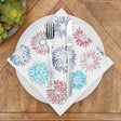 Napkin with colorful firework design on a wooden table with cutlery