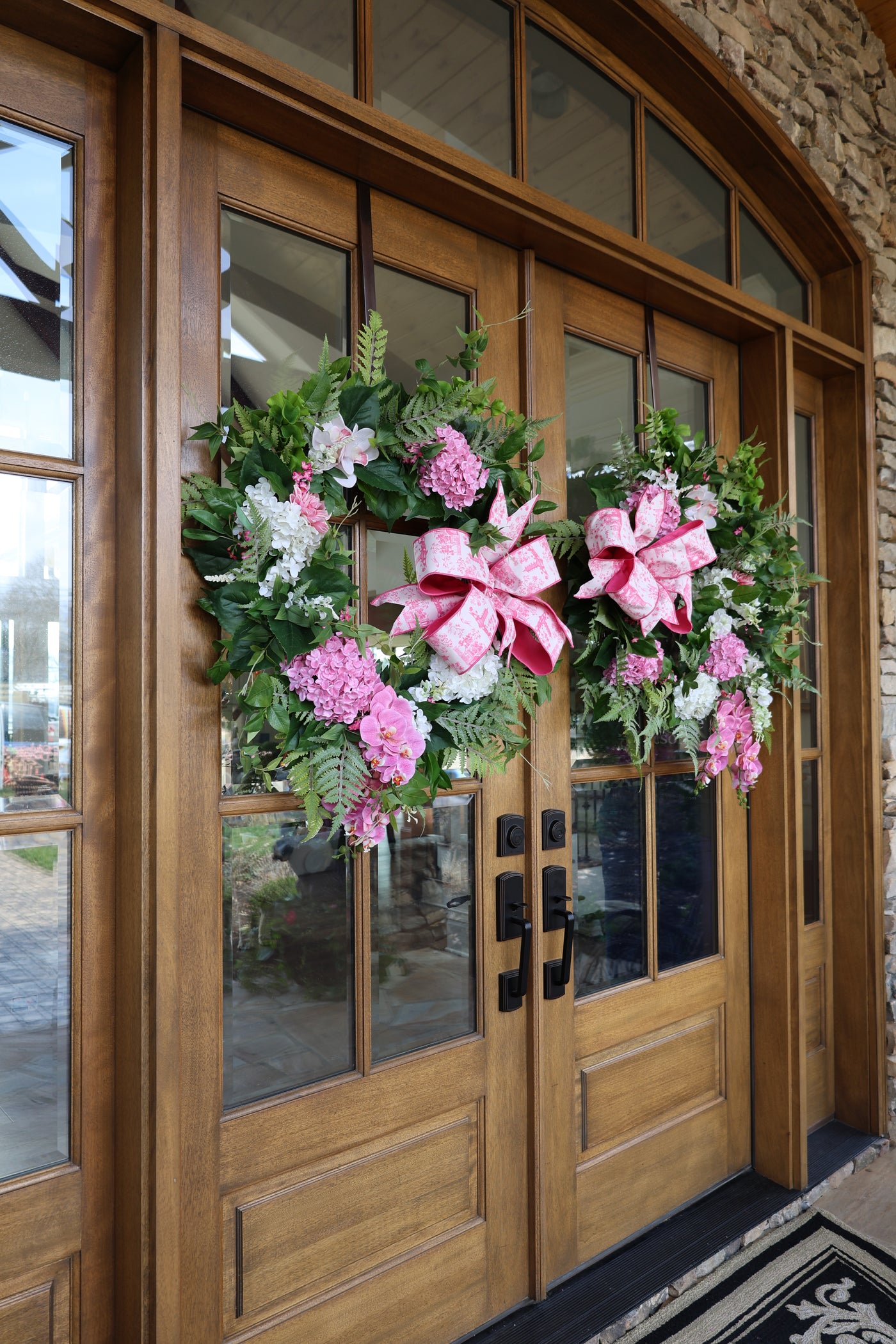Floral wreath with pink bow on a wooden door
