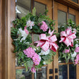 Floral wreath with pink bow on a wooden door