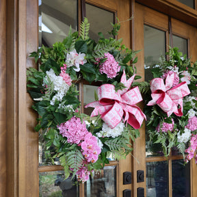 Floral wreath with pink bow on a wooden door
