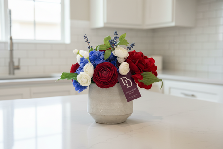 Floral arrangement in a vase on a kitchen counter with a brand tag visible.