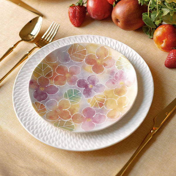 Floral-patterned plates on a table with fruit and cutlery