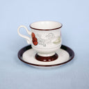 Ceramic cup and saucer with decorative elements on a light blue background