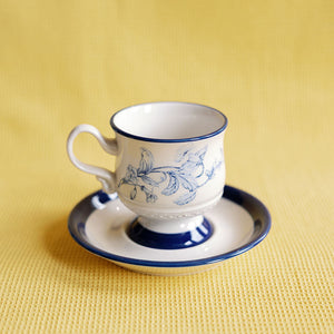 Ceramic cup and saucer with floral design on a yellow background