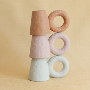 Stack of colorful ceramic taper candle holders on a beige background