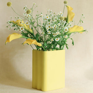 Yellow vase with flowers on a beige background