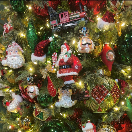 A close-up of a decorated Christmas tree with warm white lights, red and green ornaments, Santa Claus figurines, and shiny holiday baubles.