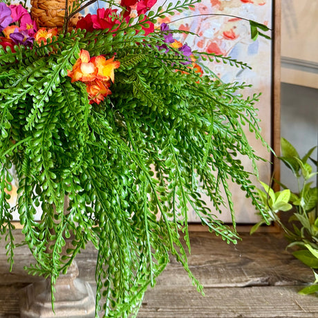 Decorative Easter arrangement with a woven basket, carrots, and flowers on a bead grass base.