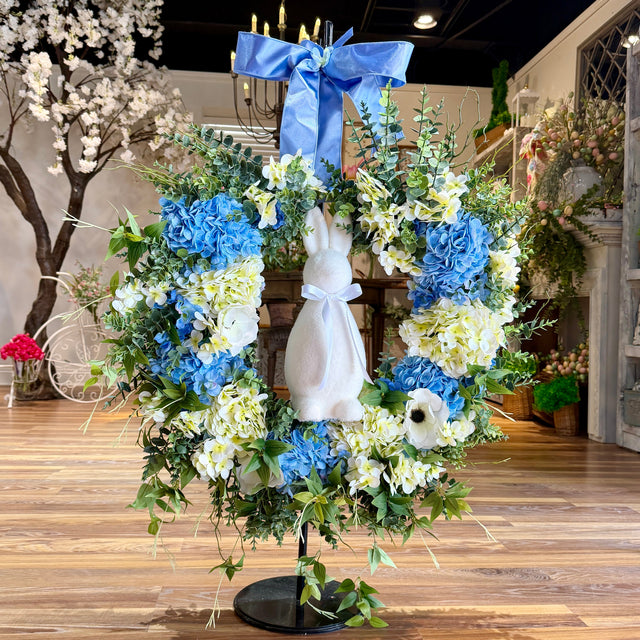 Decorative floral arrangement with blue and white flowers on a wooden floor.