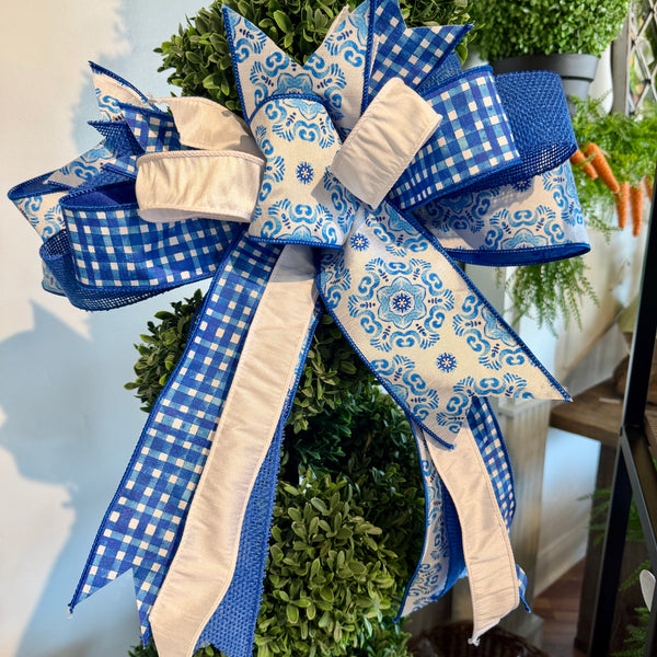 Decorative wreath with a large blue and white bow on a white wall.