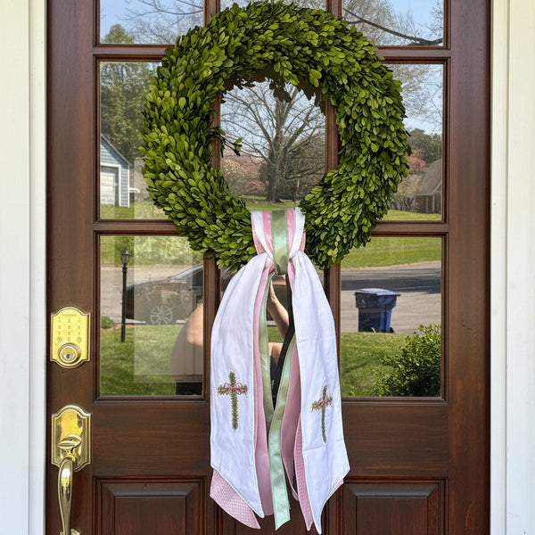 Green wreath with white ribbons on a wooden door