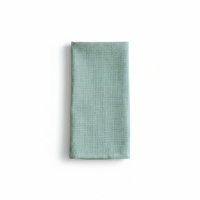 Folded light blue waffle-textured towel on a white background