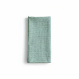 Folded light blue waffle-textured towel on a white background