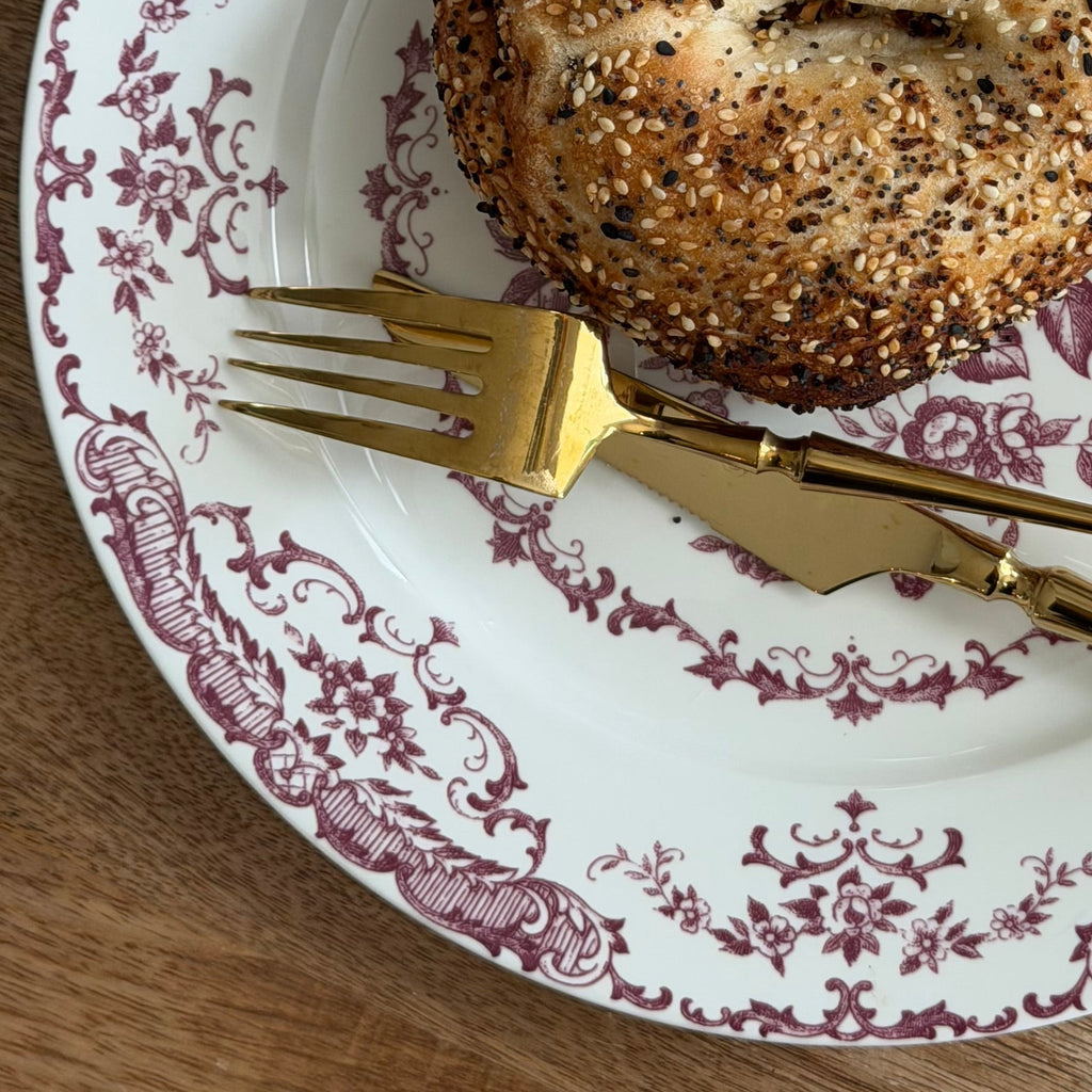 Bagel on a decorative plate with a fork on a wooden table