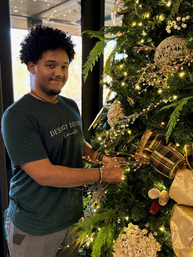 Person decorating a Christmas tree with lights and ornaments indoors.