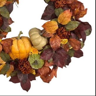 Autumn-themed wreath with pumpkins and leaves on a white door.