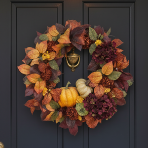 Decorative wreath with pumpkins on a blue door with potted plants on either side.