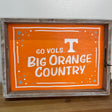 Decorative sign with 'GO VOLS BIG ORANGE COUNTRY' text on an orange background, framed in wood.