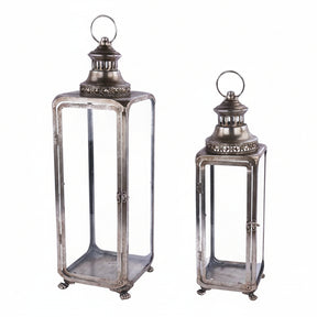 Two vintage-style metal lanterns with clear glass panels and top loop handles, shown on a plain white background.