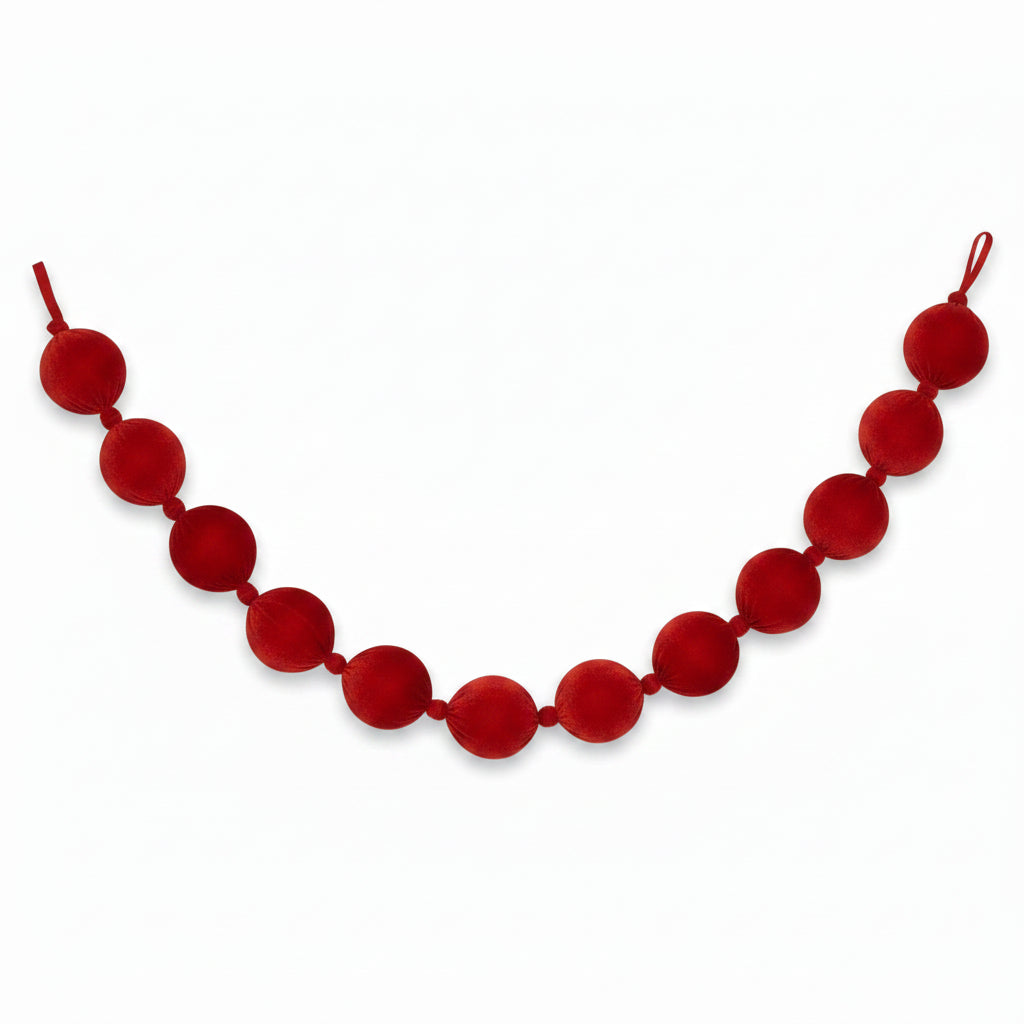 A red velvet ball garland made of large, round fabric balls strung on a velvet cord, shown against a plain white background.