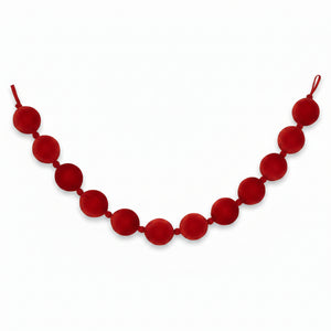 A red velvet ball garland made of large, round fabric balls strung on a velvet cord, shown against a plain white background.