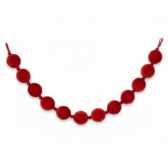 A red velvet ball garland made of large, round fabric balls strung on a velvet cord, shown against a plain white background.