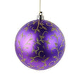 A purple Christmas or mardi gras decor bauble ornament with a gold glittery vine pattern, hanging from a thin gold string against a plain white background.