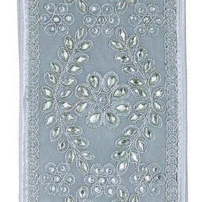 A close-up of silver fabric panel featuring intricate silver and white floral embroidery with sequins and beadwork, framed by a decorative border.