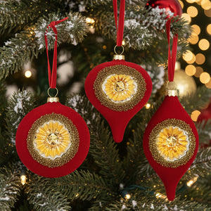 Three red Christmas ornaments with gold glitter circular medallions and red hanging ribbons, shown on a plain white background.