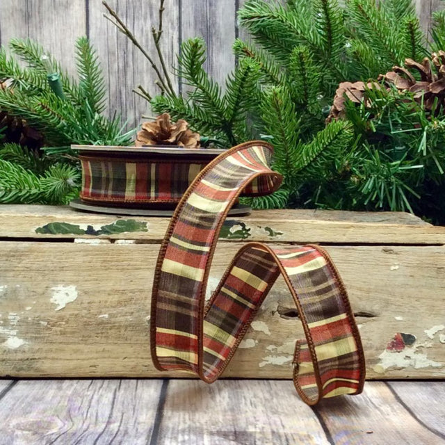 Plaid ribbon on a wooden surface with Christmas decorations in the background
